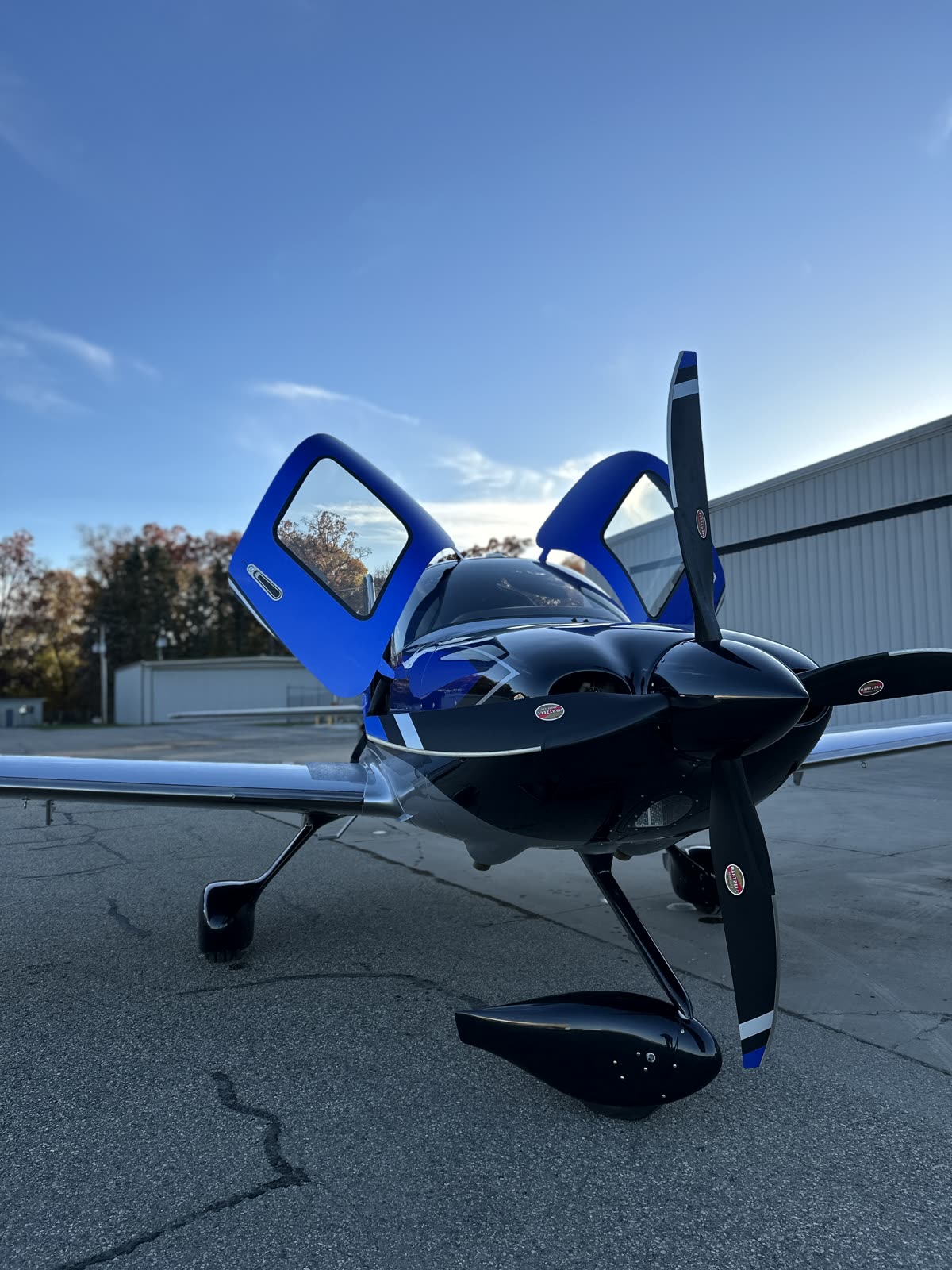 Blue and black Cirrus SR with both doors raised on the ramp at dusk
