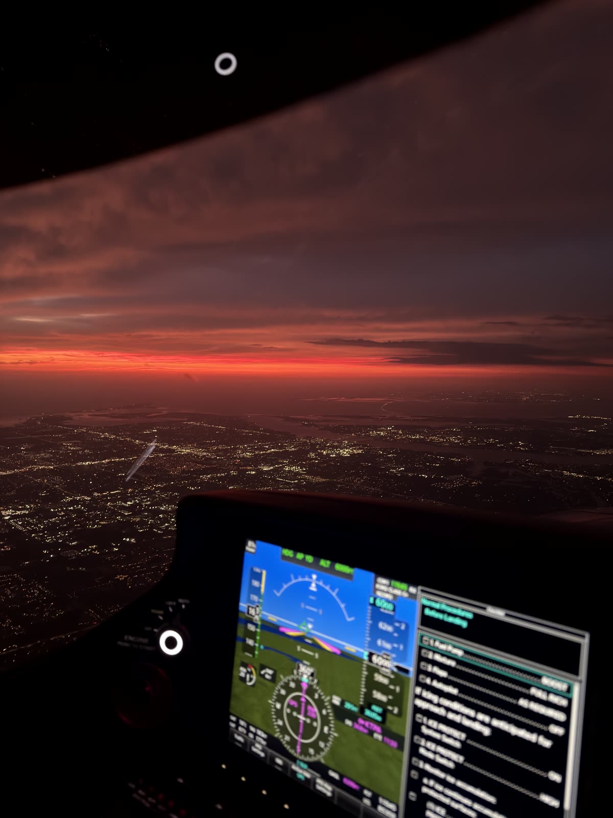 Last light on the horizon with city lights below, seen past the Garmin Perspective panel