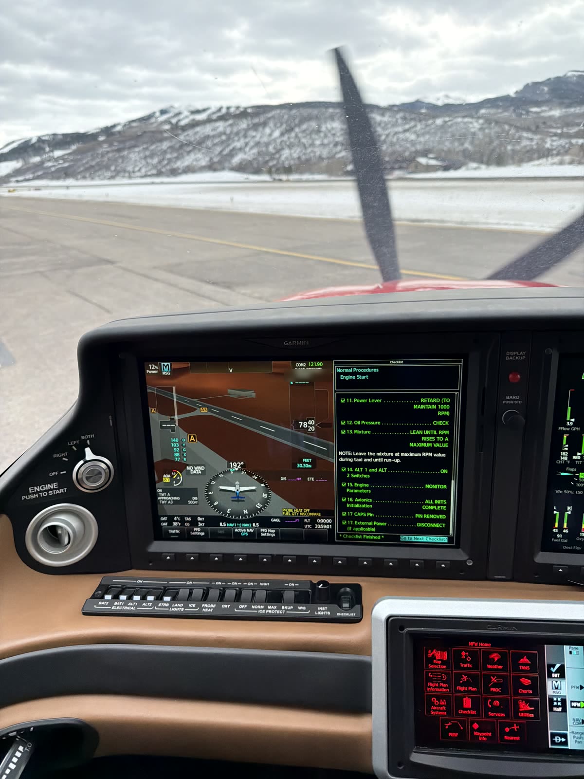 Snow-covered mountains behind the propeller during engine start at Aspen